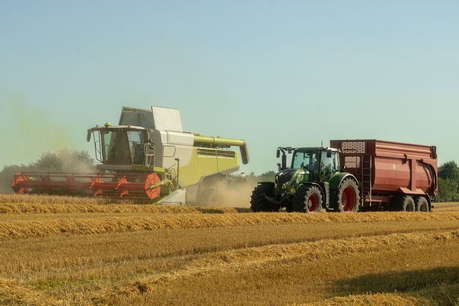Combine and tractor with grain wagon working a Midwest wheat field