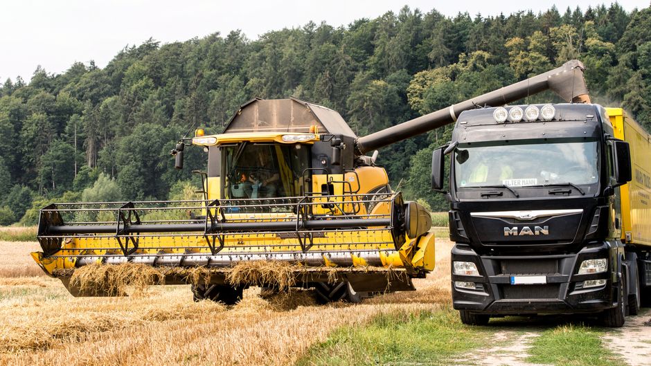 Combine unloading grain into a truck in a harvested field